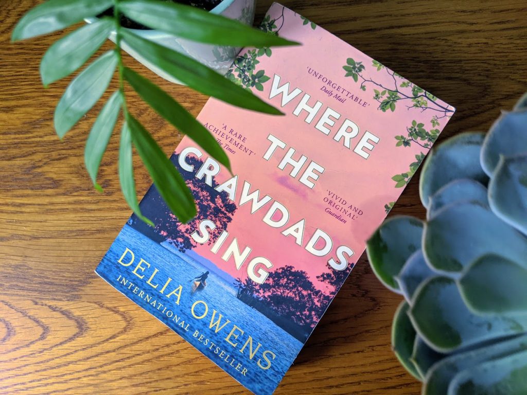 where the crawdads sing book on a wooden background with two pot plants