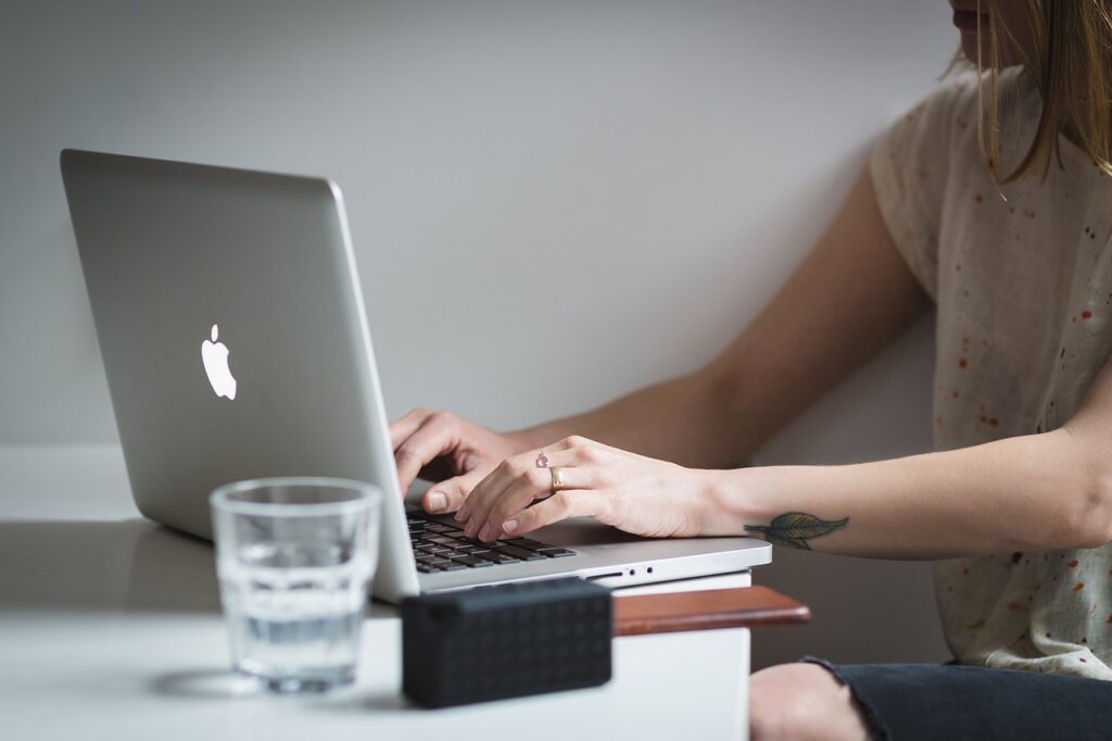 A woman typing on an Apple laptop